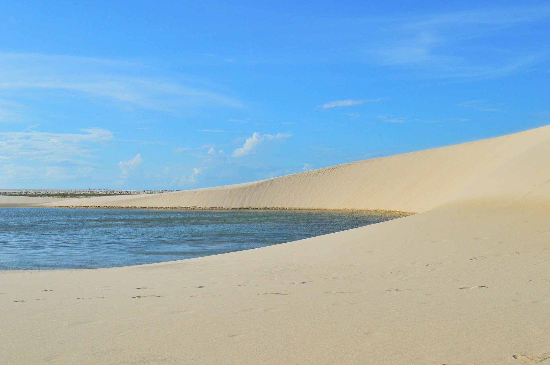 Lagoa de água azul entre dunas brancas