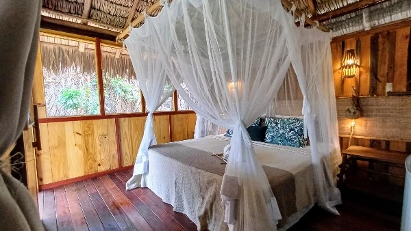 Quarto do bangalô clássico da Vila do Junco, com cama e mosquiteiro